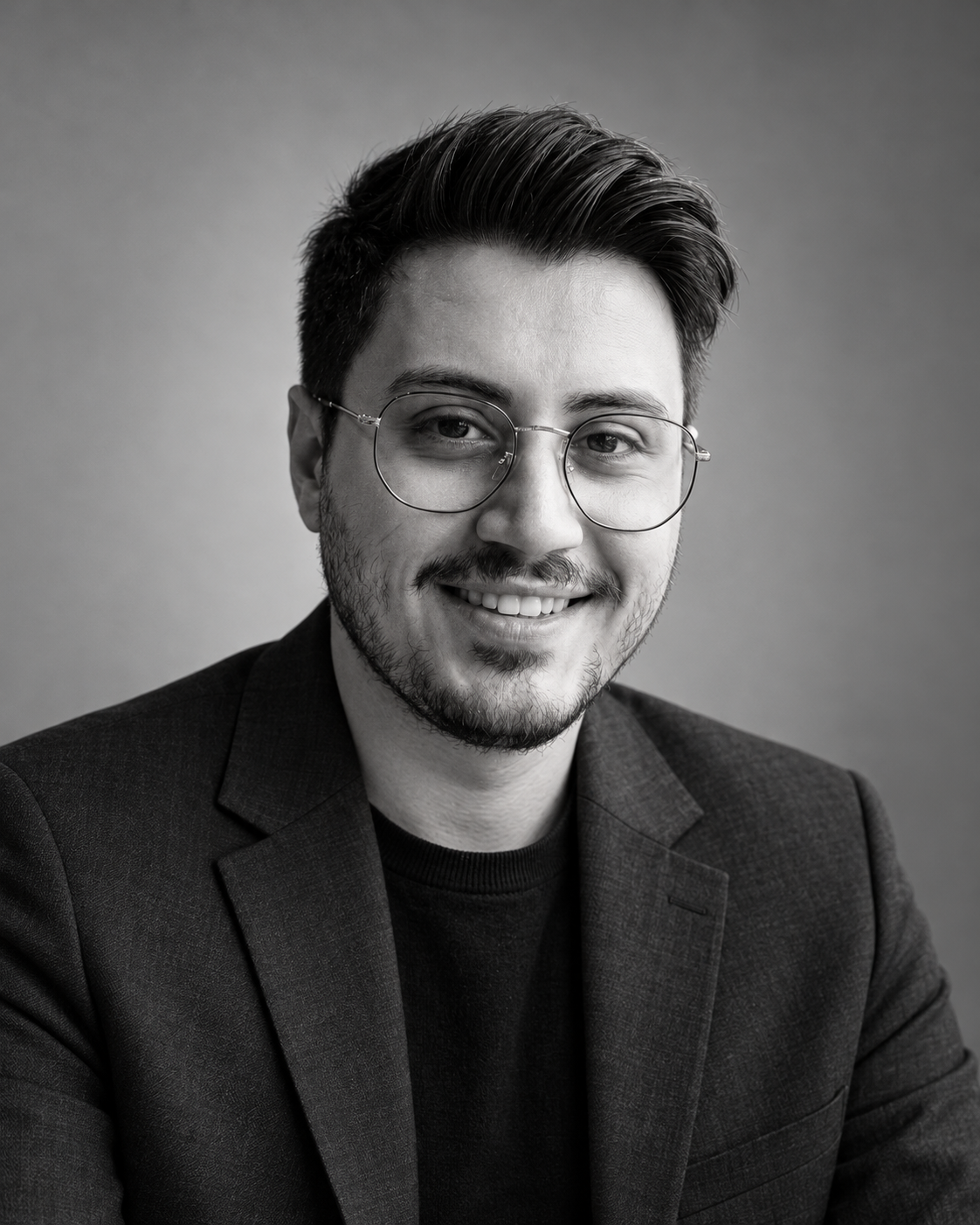 Black-and-white portrait of Abdulvahap Öğüt wearing a dark blazer and glasses